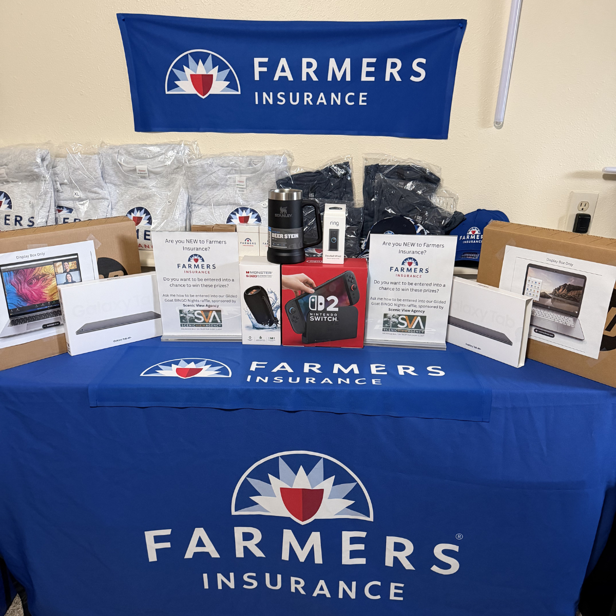 A table with Farmers Insurance logos with electronics displayed on top as prizes.